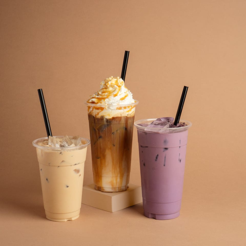 Three iced beverages: a light coffee, a caramel macchiato with whipped cream, and a purple taro drink.