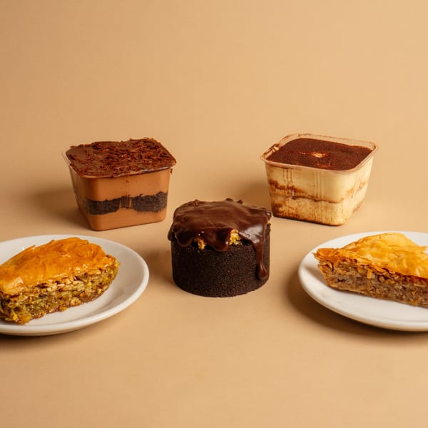 Assortment of Rendezvous International Cafe desserts: two baklava slices, a chocolate cake, and two layered parfaits.